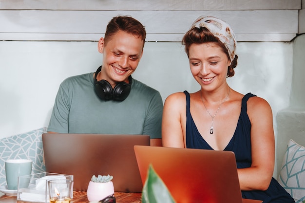 Foto paar werken op laptops aan de tafel en glimlachen