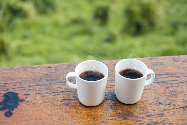 Paar witte mok warme koffie of thee op houten tafel in de ochtend met berg- en natuurachtergrond