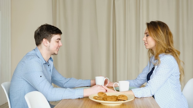 Paar zit aan tafel, slaan de handen ineen en bidden voor het ontbijt