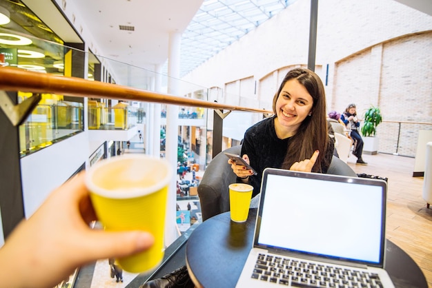 Paar zitten in café koffie drinken in gele kopjes man aan het werk op laptop terwijl vrouw haar telefoon kopieerruimte controleert