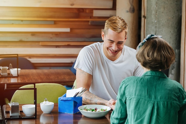 Paar zitten in een café tegenover elkaar, hand in hand Man lacht