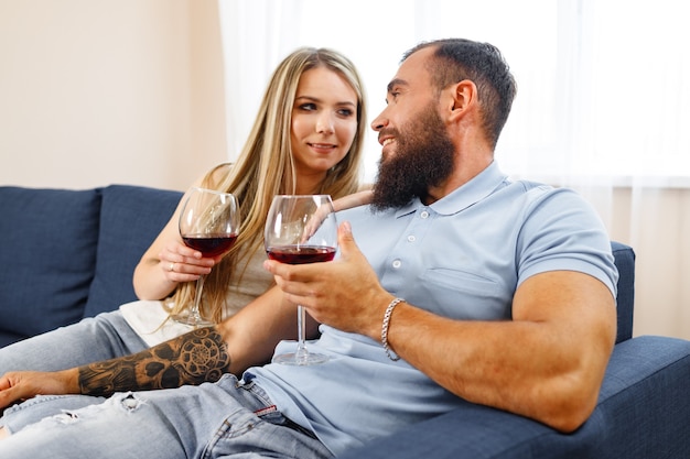 Paar zittend op de bank thuis en wijn drinken