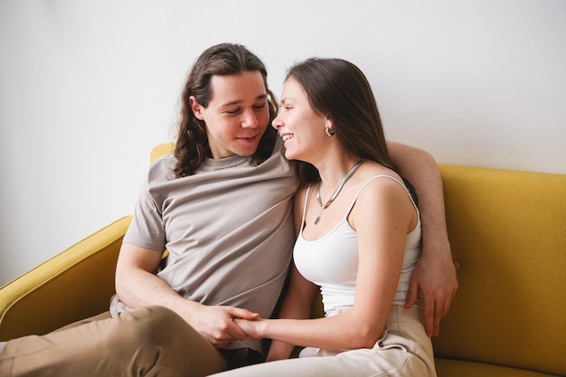 Paar zittend op gele bank in de kamer Man en vrouw verliefd in een nieuw appartement Thuiscomfort