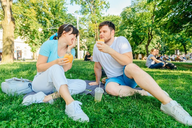 Paar zittend op groen gras hamburgers eten drinken smoothie wijde engel