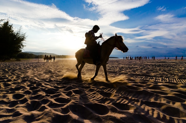 Paardrijden op het strand bij zonsondergang