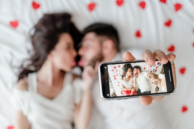 Paarman en vrouw die selfie op telefoon op bed thuis maken