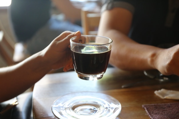 Paarmensen met zwart heet koffieglas en cake op houten lijst in koffiewinkel