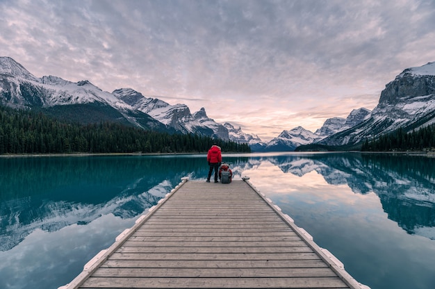 Paarreiziger het ontspannen op houten pijler in Maligne-meer bij Geesteiland, het nationale park van de Jaspis