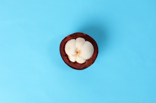 Paars mangosteenfruit gepeld half op blauwe achtergrond