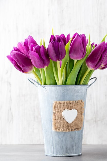 Paars tulpenboeket op de grijze muur.