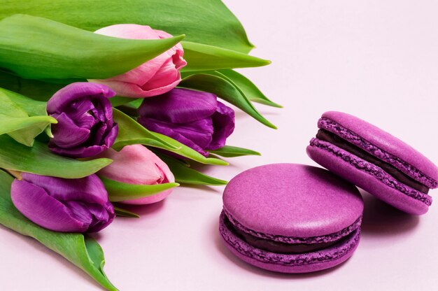 Paarse bitterkoekjes, boeket van paarse en roze tulpen op een lichtroze achtergrond