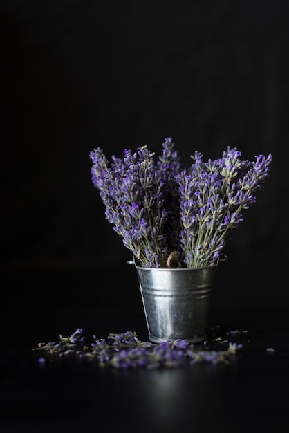 Paarse boeketten geurige lavendel staan in een emmer op zwart. plaats onder het opschrift.