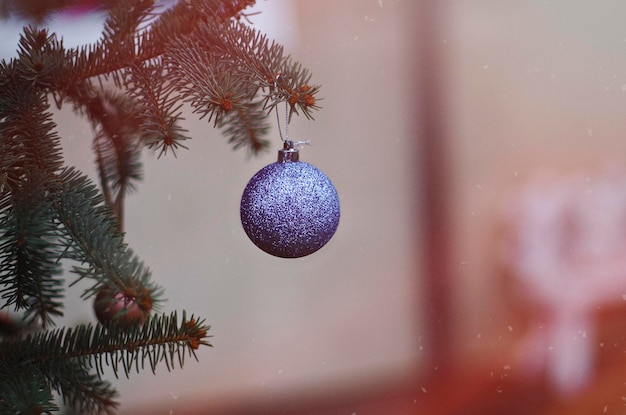 Paarse glitter kerstbal hangend aan een kerstboomtak