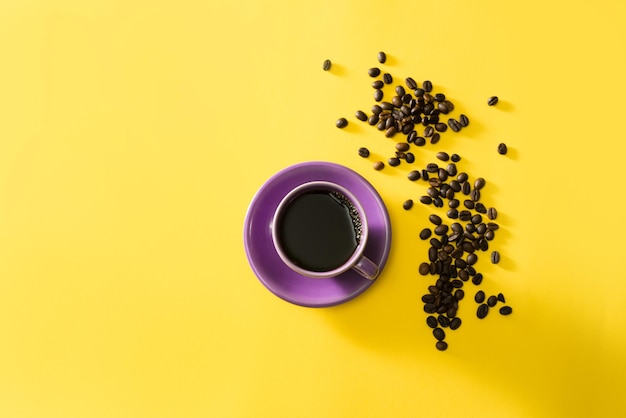 Paarse kop koffie met koffiebonen op gele achtergrond