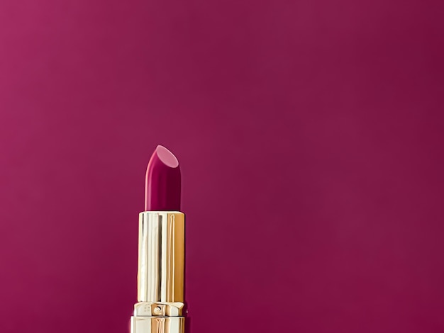 Paarse lippenstift in gouden buis op kleur achtergrond luxe make-up en cosmetica voor schoonheid merk product design