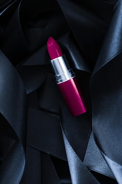 Paarse lippenstift op zwarte zijde achtergrond luxe make-up en schoonheidsmiddel