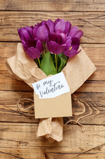 Paarse tulpen Boeket en kaart BE MY VALENTINE op houten tafel