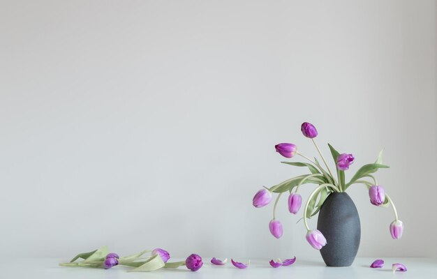 Foto paarse tulpen op een witte plank op de achtergrondmuur
