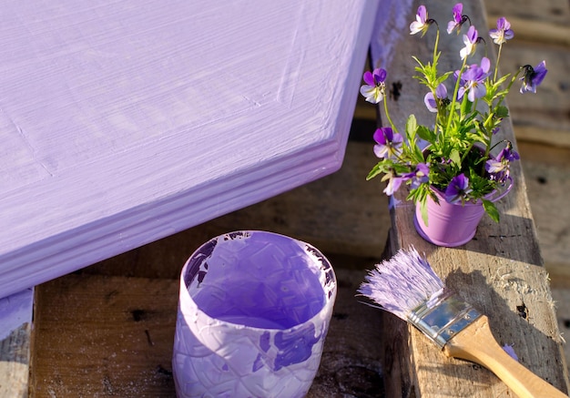 Foto paarse verf in een pot en penseel op de achtergrond van geschilderde planken