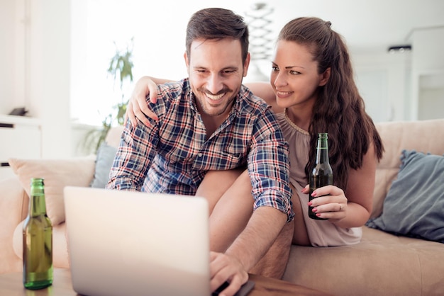 Paarzitting op bank en het gebruiken van laptop in woonkamer