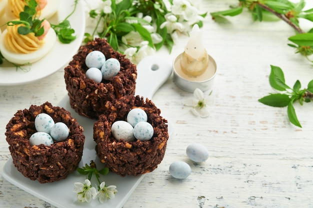 Paasbrunch of ontbijt Paaschocolade-nestcake met chocoladesuikergoedeieren traditionele warme kruisbroodjes en deviled eggs met boeketten van bloeiende appelbomen Lente Paasvakantie voedselconcept