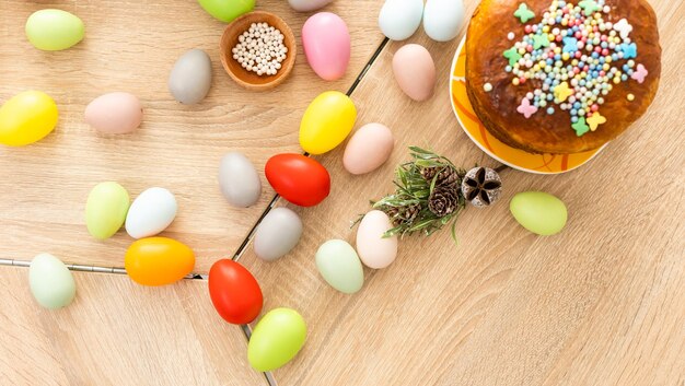 Paascake met hagelslag, beschilderde eieren en bloemen op houten tafel, plat gelegd. Ruimte voor tekst