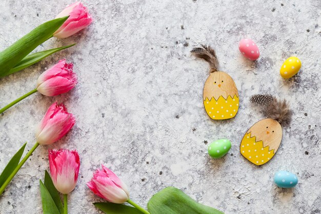 Paascompositie met roze tulpen houten kippenspeelgoed kleurrijke eieren en kopieerruimte