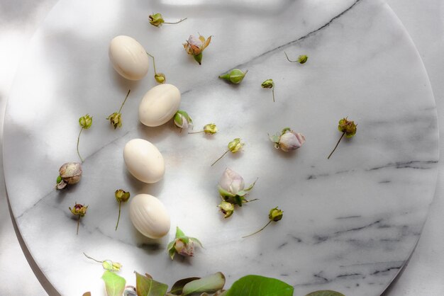 Foto paascompositie met witte chocolade-eieren en lentebladeren en bloesem op pastelkleurig marmer