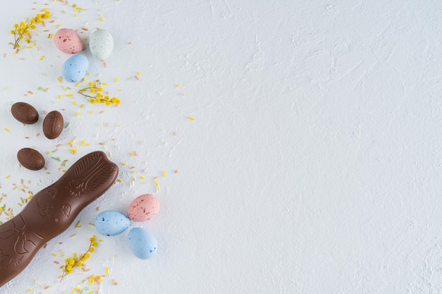 Paaseieren en chocoladekonijntje op witte achtergrond met gele bloemdecoraties