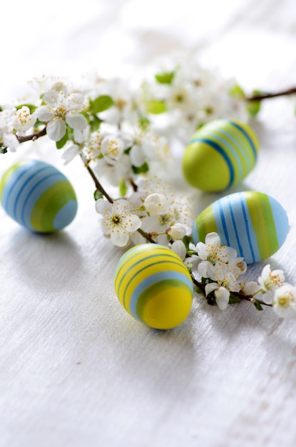 Paaseieren en tak met bloemen op houten achtergrond