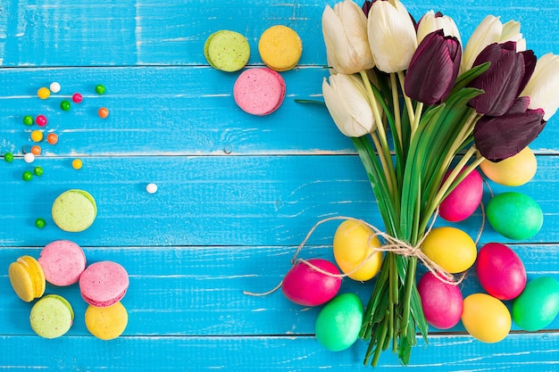 Paaseieren en tulpen op blauwe houten planken