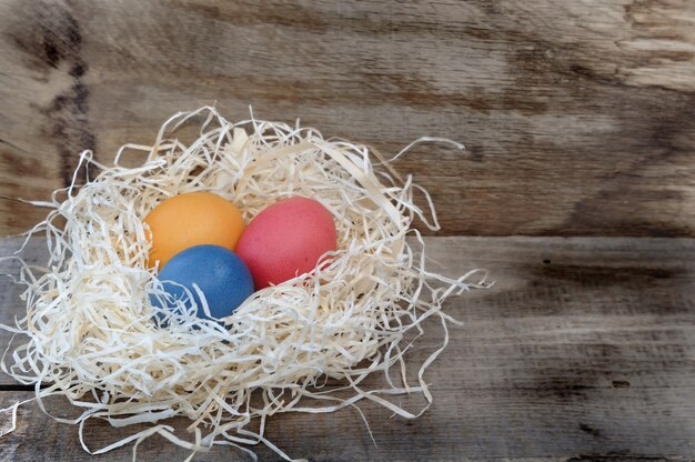 Foto paaseieren geschilderd in een nest op houten achtergrond