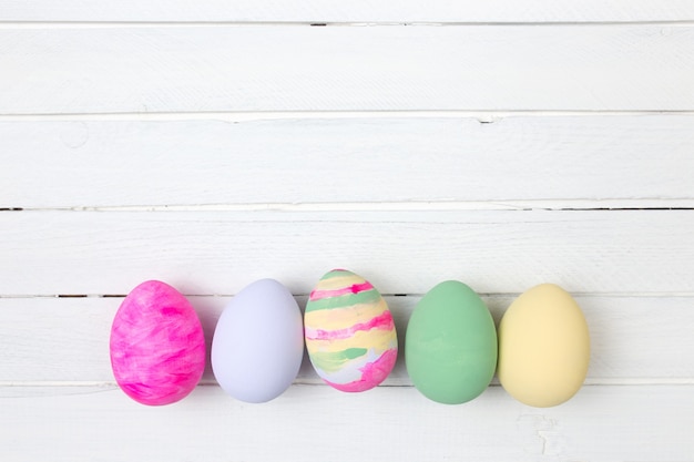 Paaseieren geschilderd in pastelkleuren op witte houten achtergrond