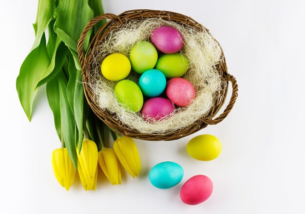 Paaseieren in een mand met tulpen op een witte achtergrond