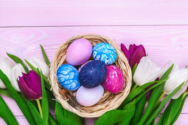 Paaseieren in een nest en tulpen op houten planken