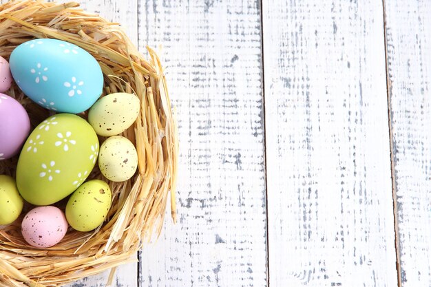 Paaseieren in nest op kleuren houten achtergrond