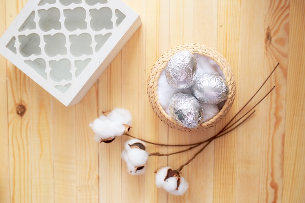 Paaseieren op witte houten lijst. bloemen en snoepjes rondom.