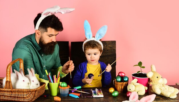 Paasfamilie in konijnenoren die paaseieren schilderen schattige kleine kindjongen in konijnenoren op paasdag