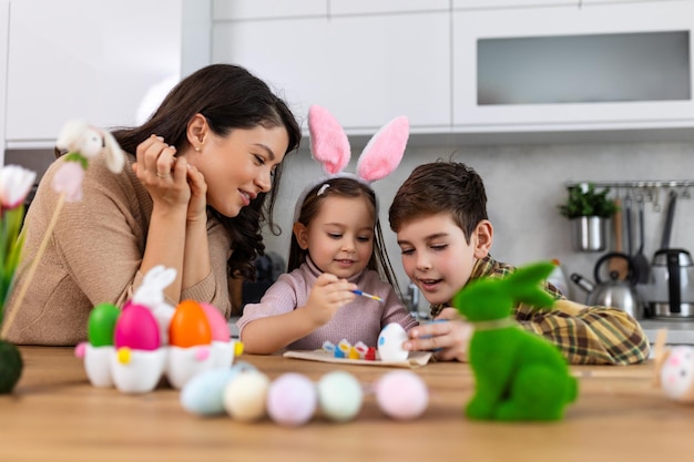 Paasfamilie vakantie en kind concept close-up van klein meisje jongen en moeder kleuren eieren voor paas Happy Family Schilderen paaseieren op keukentafel