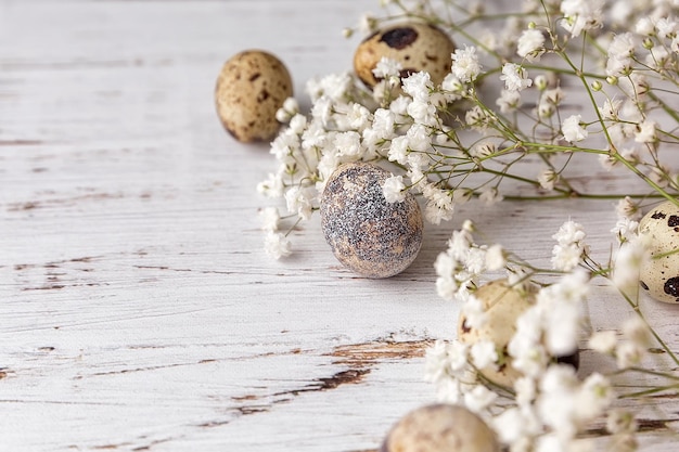 Paasfoto met kwartel eieren en kleine bloemen op een lichte houten achtergrond