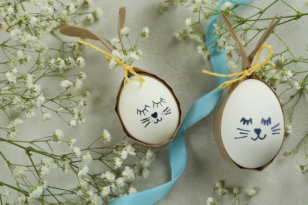 Paashazen gemaakt van eieren, lint en gypsophila bloemen op witte gestructureerde achtergrond
