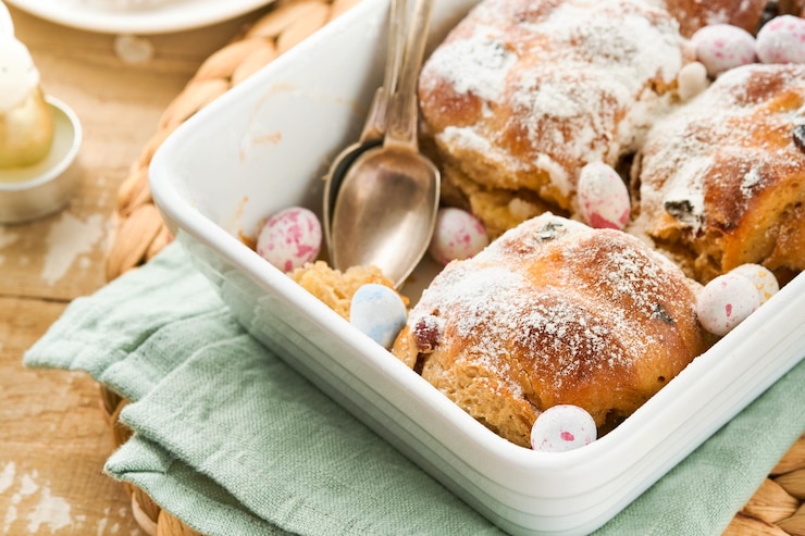 Foto paashot cross buns traditionele paas traktaties cross buns met rozijnen boter chocolade snoep eieren met bloeiende kersen of appelbloemen op rustieke lichte houten achtergrond paasfeest maaltijd