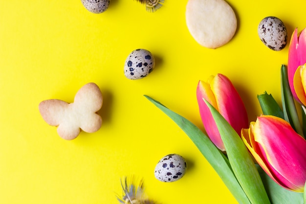 Paaskoekjes, rode en gele tulpen, kwarteleitjes op geel papier