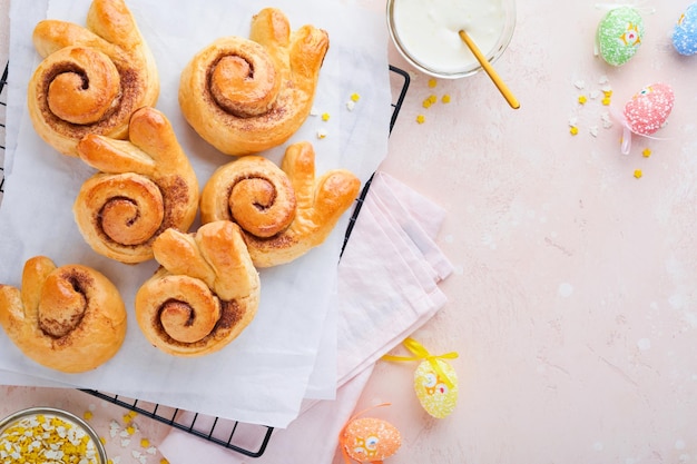 Paasontbijt Holliday concept Paashaasbroodjes rollen met kaneel gemaakt van gistdeeg met oranje glazuur paasversieringen gekleurde eieren op roze lente achtergrond Pasen Holliday kaart