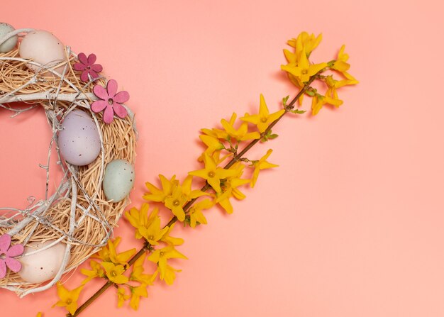 Paassamenstelling van krans met decoratieve eieren en een tak van gele bloemen