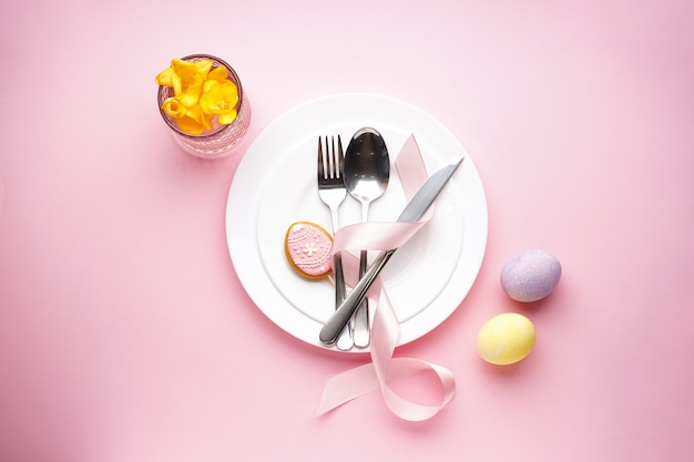 Paasvakantie concept. Paasvakantie tafel instelling op een roze oppervlak. Borden met kleurrijke eieren. Bovenaanzicht.