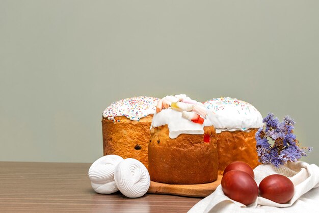 Paasvakantie food concept Zelfgemaakte paascake met witte suikerglazuur gelei snoepjes zoete poeder marsmallow versierd met gekleurde eieren bloemen bloesems op houten achtergrond met kopie ruimte