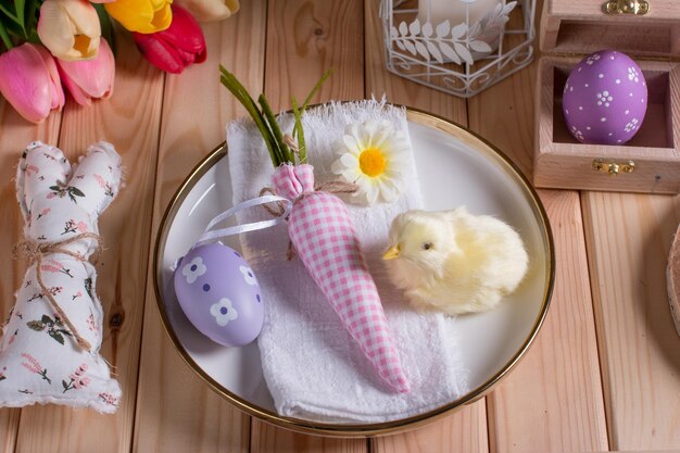 Paasversieringen op tafel een wit gebreid servet Tafeldecoratie konijn wortel en beschilderde eieren