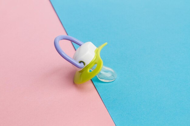 A pacifier on a pink and light blue background