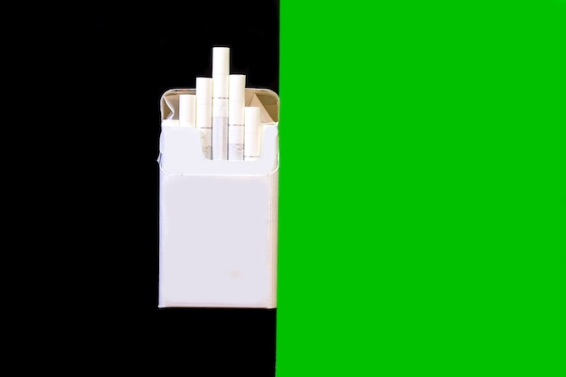 Un pacchetto di sigarette su uno sfondo scuro accanto a uno sfondo verde